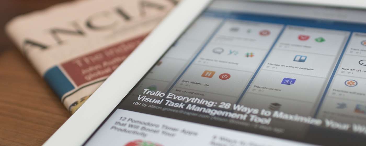 A tablet showing a news feed beside a printed newspaper